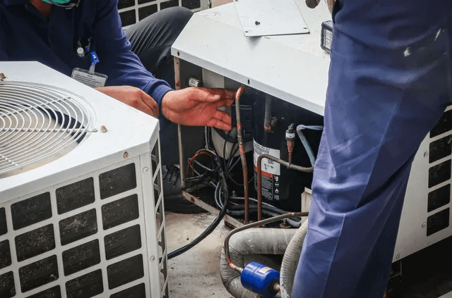Two technicians in Greenfield inspecting the inside of an AC unit